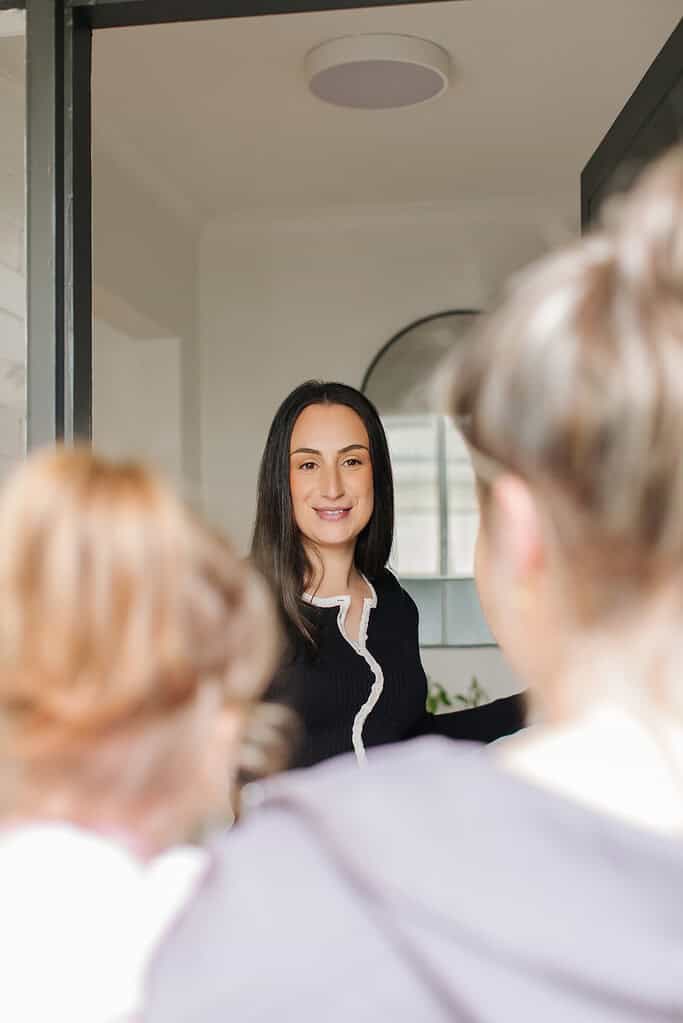 Friendly real estate agent greeting clients at Ember Estate Agents in a modern home foyer, showcasing expert property services in Australia.