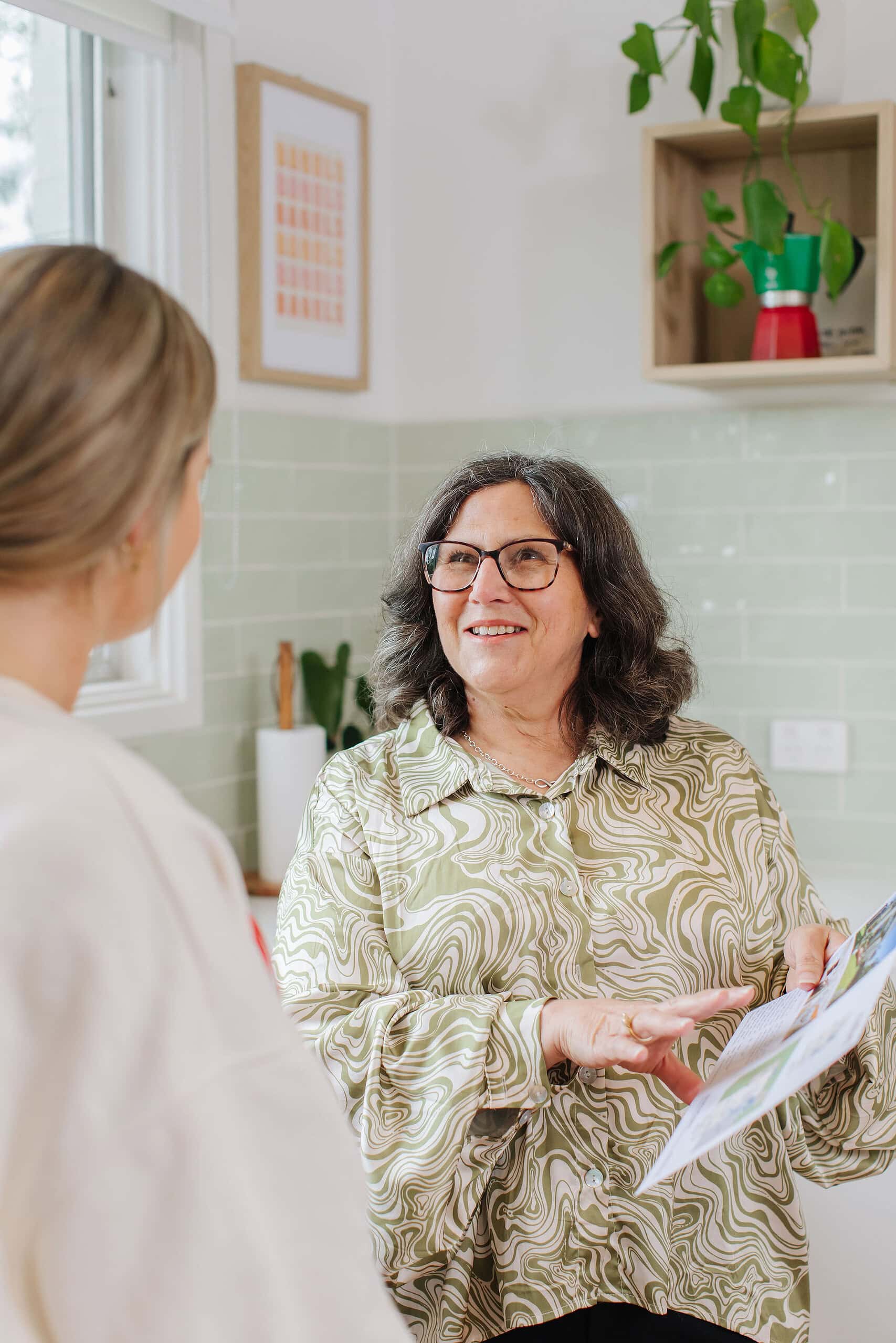 Confident female real estate agent discussing property details with a client in a well-lit, modern kitchen setting, showcasing professional property services.