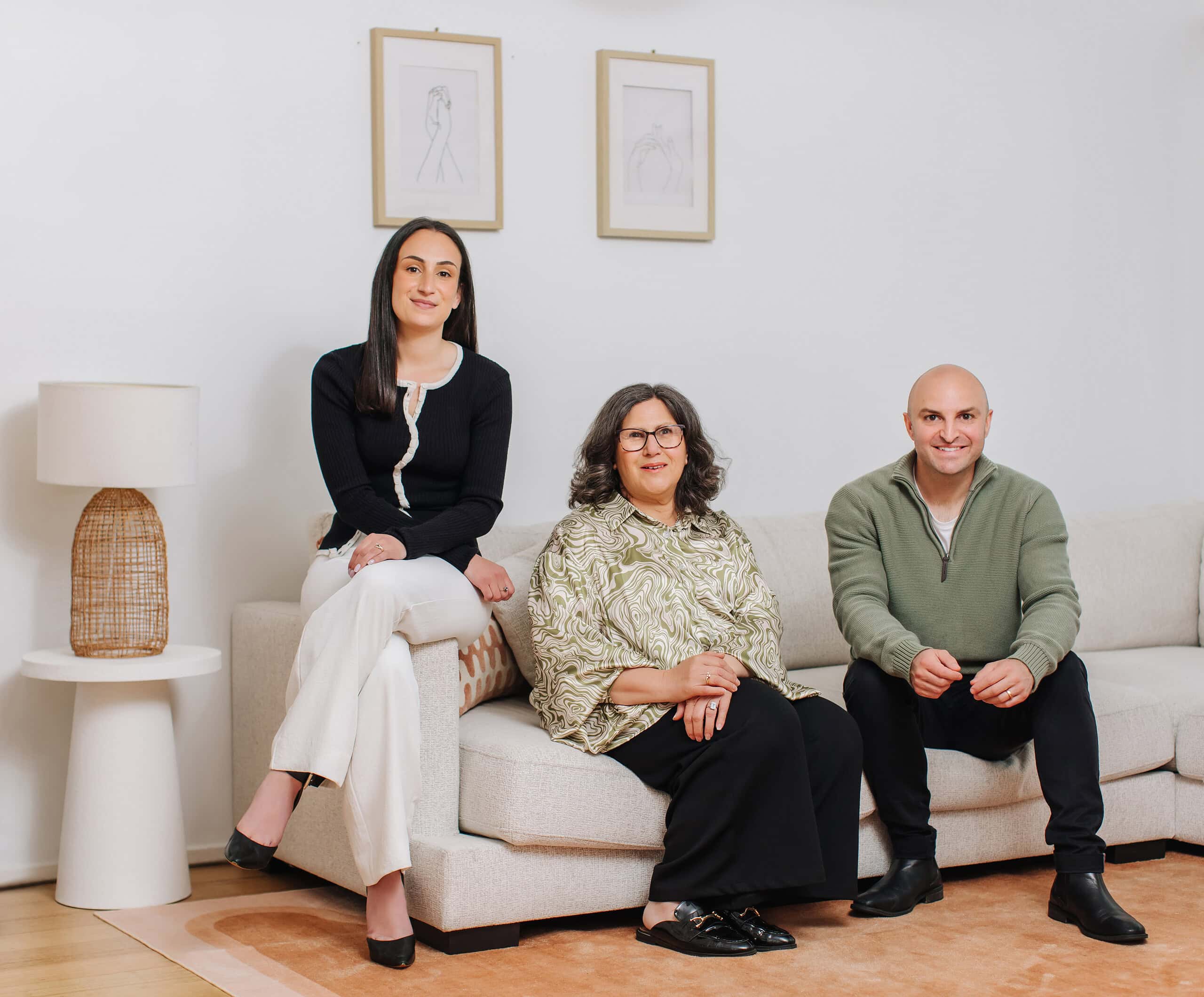 Friendly team of Ember Estate Agents sitting on a stylish sofa in a bright, modern office, showcasing professional real estate services in Australia.