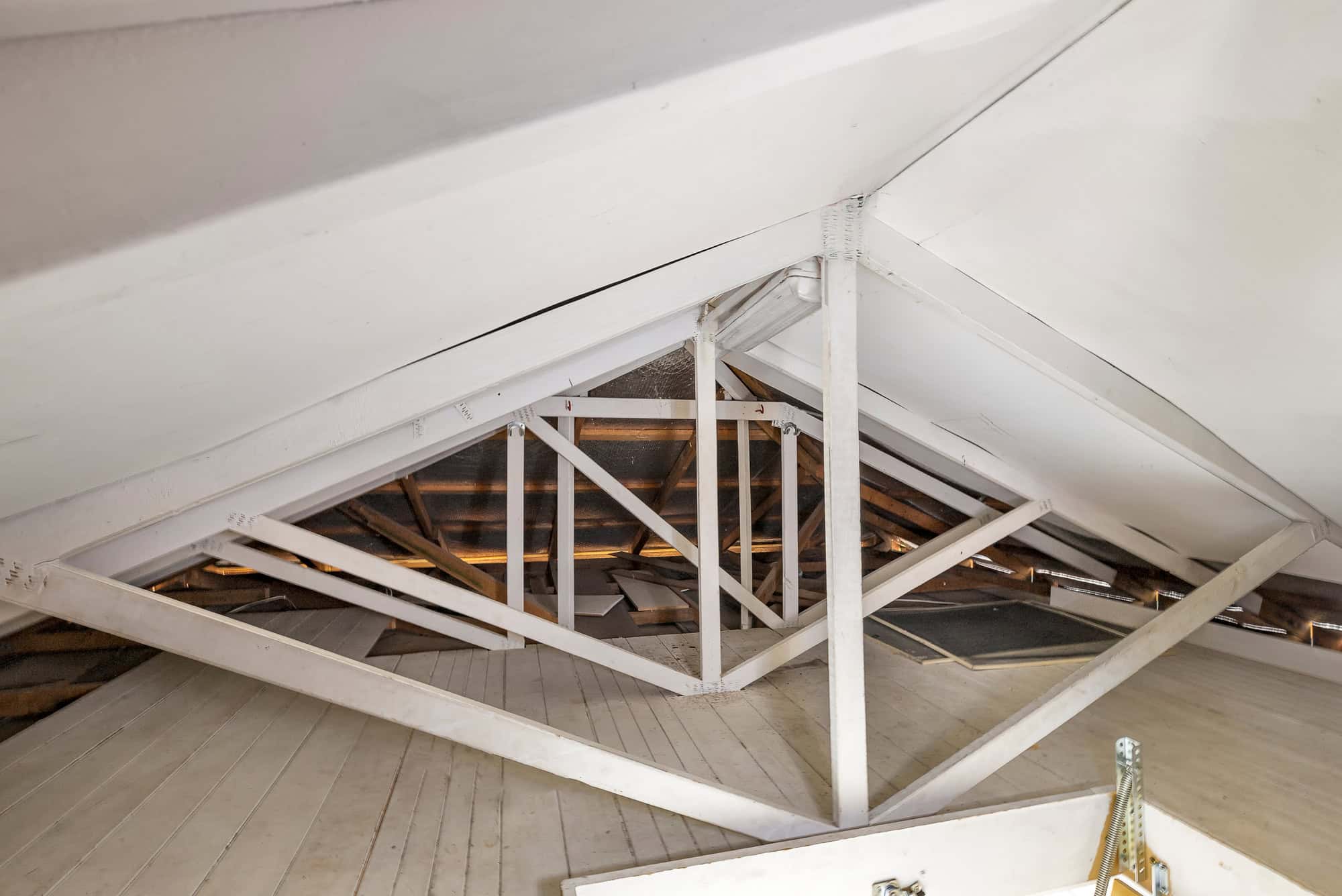 Bright attic space with white-painted beams, sloped roof, and wooden flooring, showcasing potential for home renovation and property value enhancement at Ember Estate Agents.