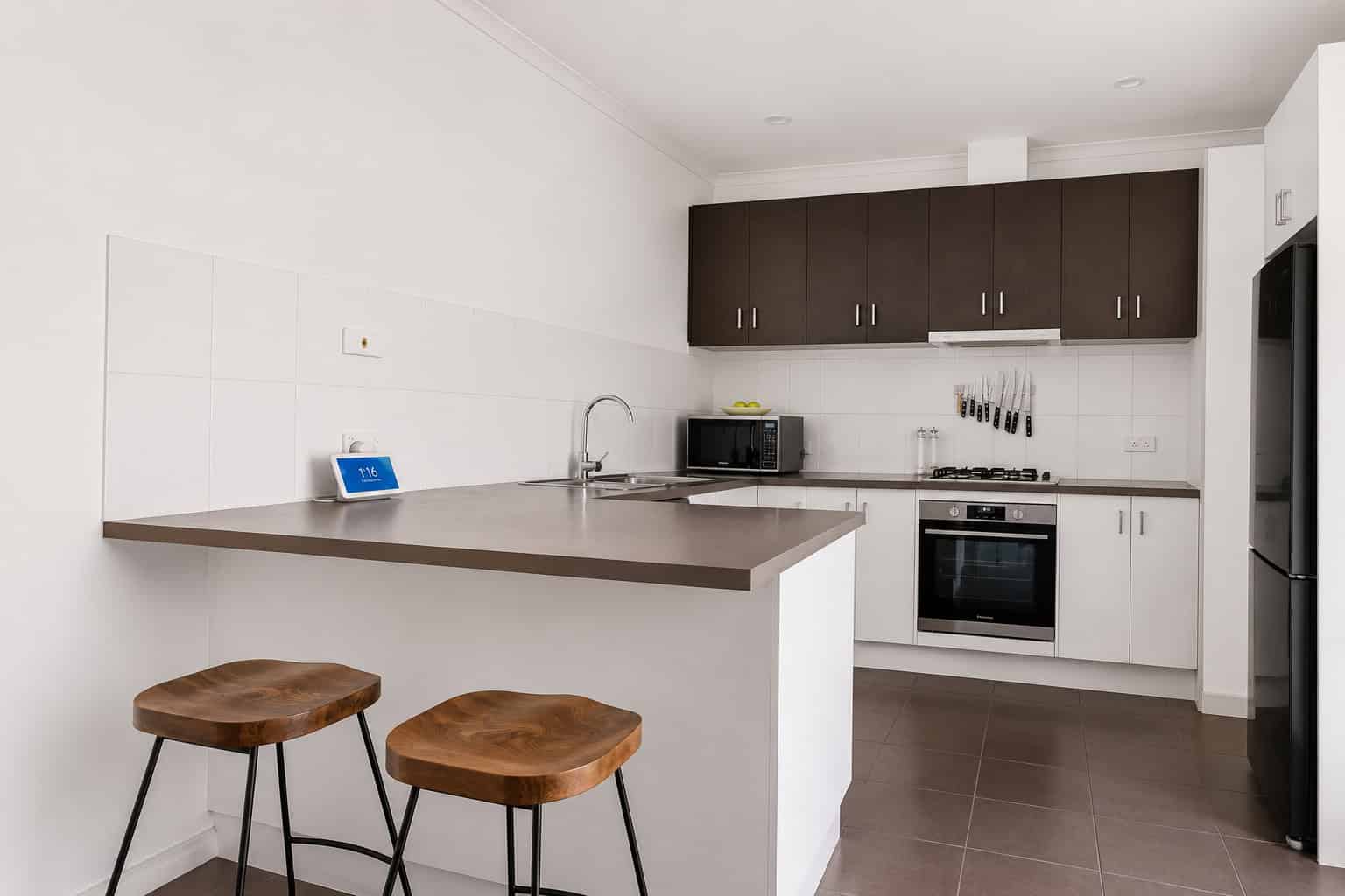 Modern kitchen with dark and white cabinetry, stainless steel appliances, and a breakfast bar in a North-facing Chelsea residence.