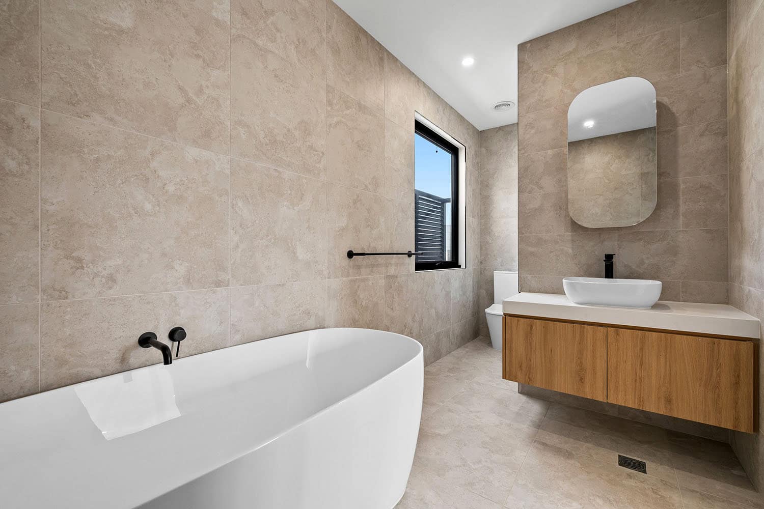 Modern bathroom with bathtub and vanity in Ember Estate Agents property listing, showcasing contemporary design, neutral tones, and natural light, ideal for luxury home buyers.