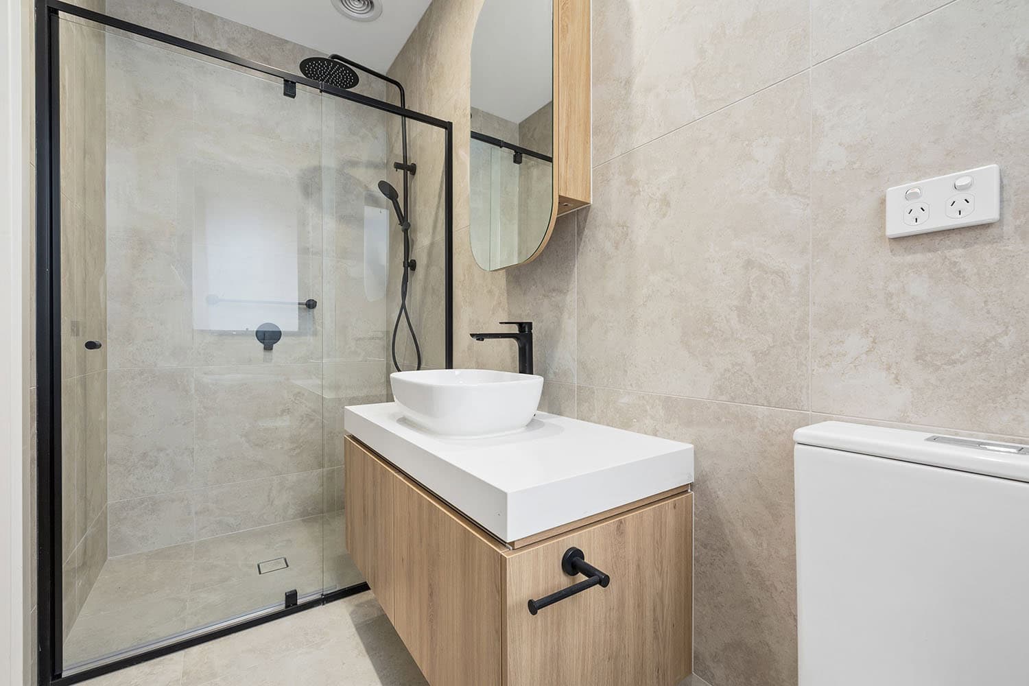 Modern bathroom featuring a walk-in shower with glass enclosure, stylish vanity with vessel sink, and neutral-toned tiles, showcasing contemporary property design by Ember Estate Agents.