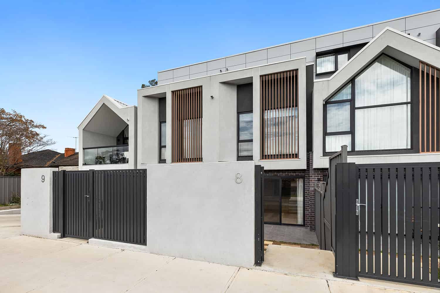Modern residential building with sleek design, large windows, and wooden accents, showcasing contemporary architecture in a suburban setting.