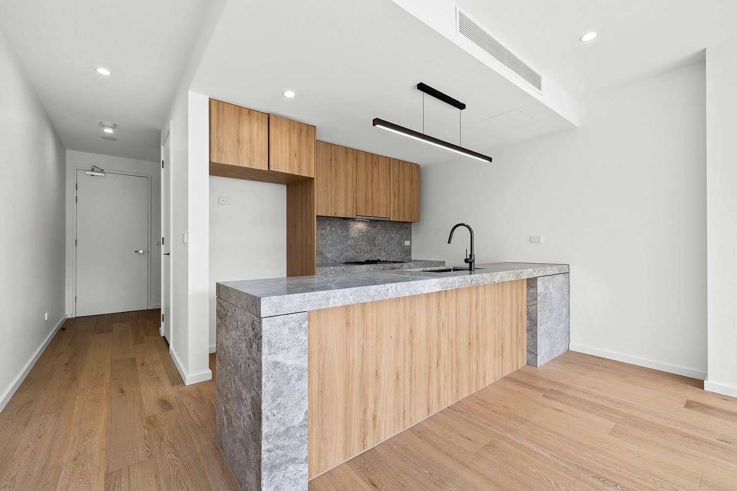 Contemporary kitchen featuring sleek wooden cabinets, a grey stone countertop, and minimalist design elements, perfect for modern living spaces in Ember Estate.